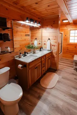 a bathroom with a toilet and a sink in a log cabin at Sleeps 16 Luxury Cabin with Game Room & Hot Tub in Logan