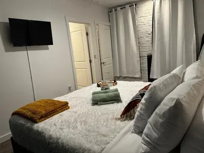 a bedroom with a white bed with a television on the wall at Jungle House Columbus Downtown Free Parking Sleeps 8 - Steps to Convention Center & Nationwide Arena - 2BR Short North Luxury Home - Over 5,800 Five Star Stays in Columbus