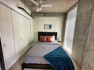 a bedroom with a bed with a blue blanket on it at 3 Brand new combined apartments with city views in Cleveland