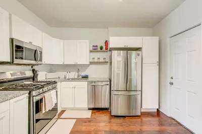 a kitchen with white cabinets and a stainless steel refrigerator at 6 Mi to Ohio State Walkable Home in S Columbus! in Columbus