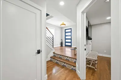 a hallway with white walls and a staircase with a chair at 1BR, Next to Monastery Wedding Venue, with Bathtub in Cincinnati