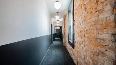 a hallway with a red brick wall and lights at Pickle Factory Hotel - 2BR Next to Wenzel Distillery in Covington