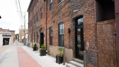 a brick building with potted plants on a street at Pickle Factory Hotel - 1BR Beside New Distillery! in Covington