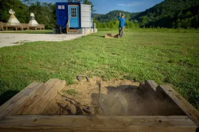 a man standing in a field with a fire pit at Furnished Glamping Tent/Red River Access/King Bed in Stanton