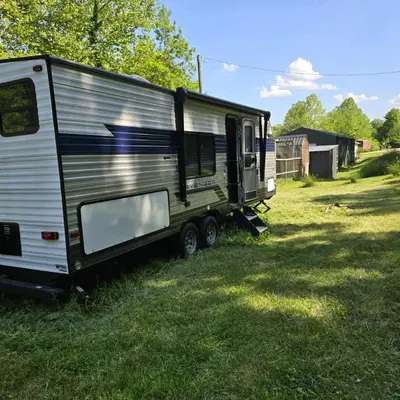 a trailer sitting in the grass in a field at Monday creek camper in New Straitsville
