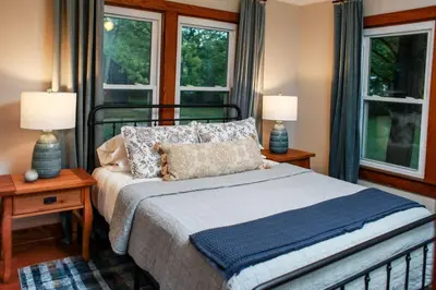 a bedroom with a bed with two lamps and two windows at WiFi & Pets - Alice Rocks - Cave Run Lake & RRG KY in Frenchburg