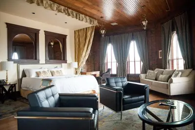 a bedroom with a bed and a couch and chairs at The Hackett Hotel in Marietta
