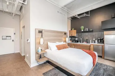 a bedroom with a large bed and a kitchen at The 333 Suites - For 24 Guests in Cincinnati