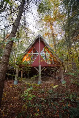 a red house in the middle of a forest at Waterfront A- Frame with Dock, Canoe + Kayaks in Rockbridge