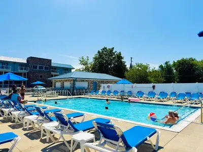a swimming pool with blue chairs and people in it at Put-in-Bay Poolview Condo #6 in Put-in-Bay