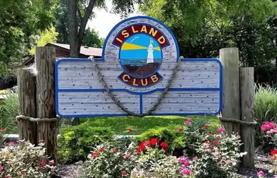 a blue sign for a marina club with flowers at Put-in-Bay Island Club #98 in Put-in-Bay