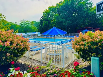 a pool with a blue umbrella and chairs and flowers at Put-in-Bay Island Club #68 in Put-in-Bay