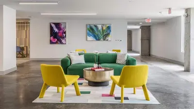 a living room with a green couch and two yellow chairs at Modern apt in Cincy stadiums and with river views in Cincinnati