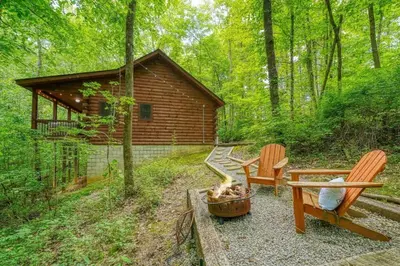 a backyard with two chairs and a fire pit and a cabin at Romantic Logan Cabin with Private Year Round Hot Tub Near Hocking Hills in Logan