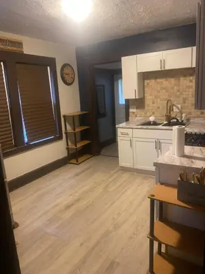 a kitchen with white cabinets and a wooden floor at 1469 east 116th in Cleveland