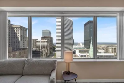 a living room with a couch and a large window at LAKE VIEWS! 15th Floor Downtown High-Rise | Gym in Cleveland