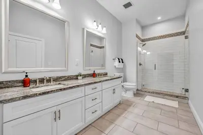 a white bathroom with two sinks and a toilet at Super LUX Downtown 1BD Condo | Gym | 24/7 Security in Cleveland