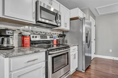 a kitchen with white cabinets and a stainless steel refrigerator at Elegant Loft in the Heart of Downtown | Gym in Cleveland