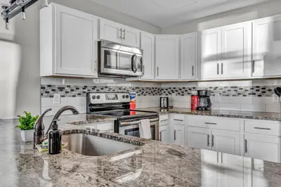 a kitchen with white cabinets and a sink and a microwave at Elegant Downtown Apartment | Paid Parking & Gym in Cleveland