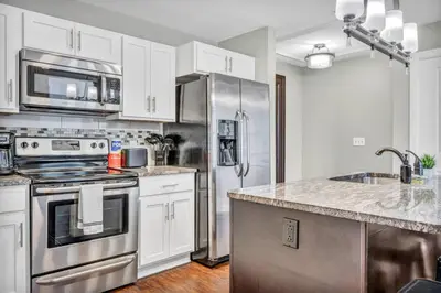 a kitchen with white cabinets and a stainless steel refrigerator at Luxury 2 Bedroom Loft in Heart of Downtown | Gym in Cleveland