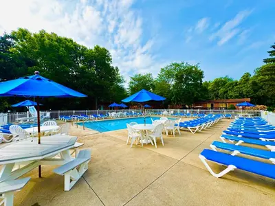 a pool with blue umbrellas and white chairs and tables at Put-in-Bay Island Club #101 in Put-in-Bay