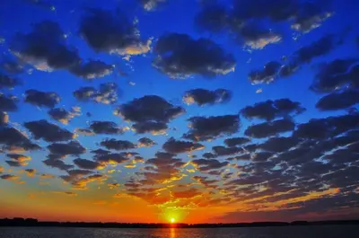 a sunset with clouds in the sky over the water at Put-in-Bay Poolview Condo #3 in Put-in-Bay