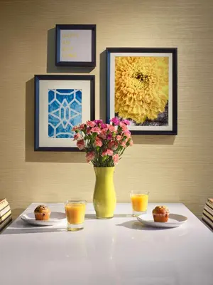a table with a yellow vase with flowers and cups at Sonesta ES Suites Cincinnati - Sharonville East in Sharonville