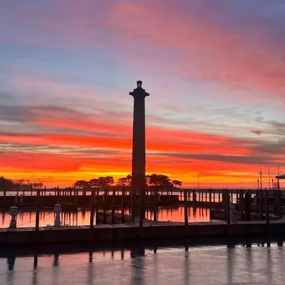 a lighthouse in the water with a sunset in the background at Put-in-Bay Waterfront Condo #109 in Put-in-Bay