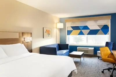 a hotel room with a bed and a chair and a window at Holiday Inn Express Hotel & Suites Cincinnati Southeast Newport by IHG in Bellevue