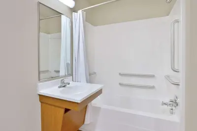 a white bathroom with a sink and a shower at WoodSpring Suites Fort Wayne in Fort Wayne