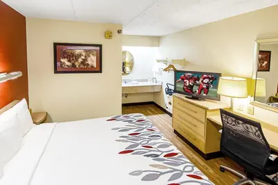 a hotel room with a bed and a desk with a computer at Red Roof Inn Huntington in Barboursville
