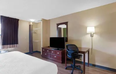 a hotel room with a bed and a desk with a television at Extended Stay America Suites - Columbus - Dublin in Dublin