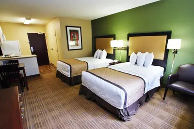a hotel room with two beds and a chair at Extended Stay America Suites - Cincinnati - Covington in Covington