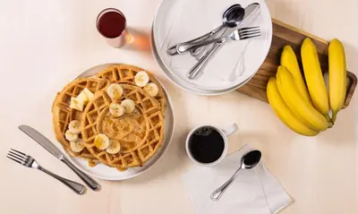 a table topped with a plate of waffles and bananas at Drury Inn & Suites Middletown Franklin in Middletown