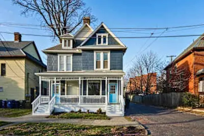 a blue house with a white porch at Jungle House Luxury Homes - Columbus Downtown Short North - Steps to Convention Center & Nationwide Arena - Sleeps up to 11 - Free Parking - Over 5,800 Five Stars in Columbus