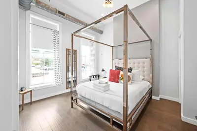 a bedroom with a canopy bed with white sheets and red pillows at 4 Apartments, Downtown, Walk to Cincy Stadiums! in Covington