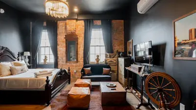 a living room with a bed and a tv and a couch at Pickle Factory Hotel - 8BR Full Hotel with Free Parking in Covington