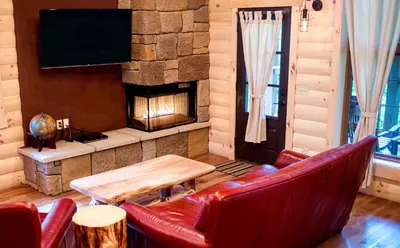 a living room with red leather chairs and a fireplace at Cricket Hill Treehouse D by Amish Country Lodging in Millersburg