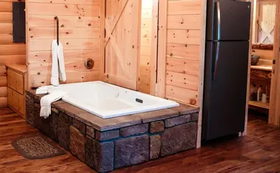 a bath tub in a room with a refrigerator at Cricket Hill Treehouse C by Amish Country Lodging in Millersburg