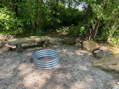 a metal barrel sitting in front of a bench at Cricket Hill Treehouse B by Amish Country Lodging in Millersburg