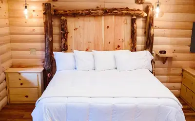 a bedroom with a white bed in a log cabin at Cricket Hill Treehouse B by Amish Country Lodging in Millersburg