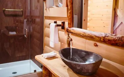 a bathroom with a sink in a log cabin at Cricket Hill Treehouse B by Amish Country Lodging in Millersburg