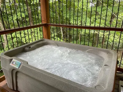a hot tub on a balcony with a fence at Treehouse #8 by Amish Country Lodging in Millersburg