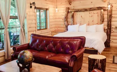 a bedroom with a bed and a leather couch at Treehouse #8 by Amish Country Lodging in Millersburg