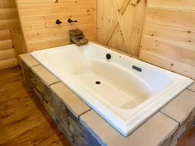 a large white tub in a room with wooden walls at Treehouse #8 by Amish Country Lodging in Millersburg