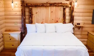 a bedroom with a white bed in a log cabin at Treehouse #5 by Amish Country Lodging in Millersburg