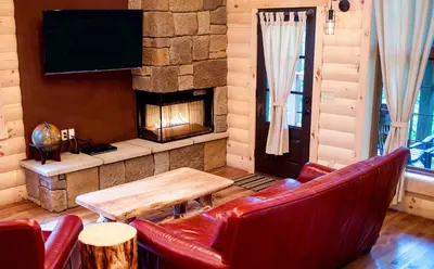 a living room with a fireplace and red leather chairs at Treehouse #5 by Amish Country Lodging in Millersburg