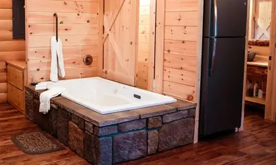 a bath tub in a room with a refrigerator at Treehouse #4 by Amish Country Lodging in Millersburg