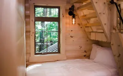 a bed in a tiny house with a window at Skyview Treehouse by Amish Country Lodging in Millersburg