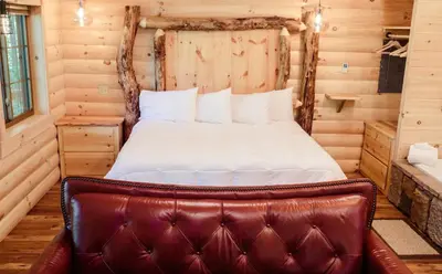 a bedroom with a bed with a leather seat at Cricket Hill Treehouse by Amish Country Lodging in Millersburg